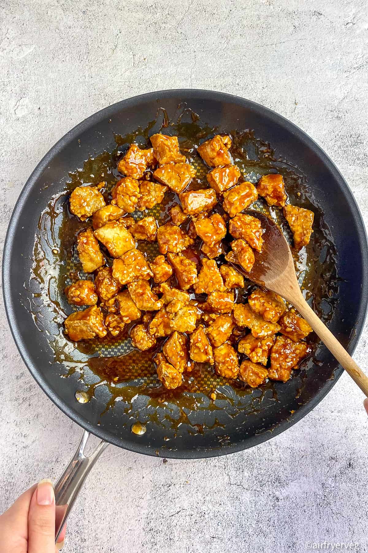 Air fryer teriyaki tofu mixed with sauce in a skillet.