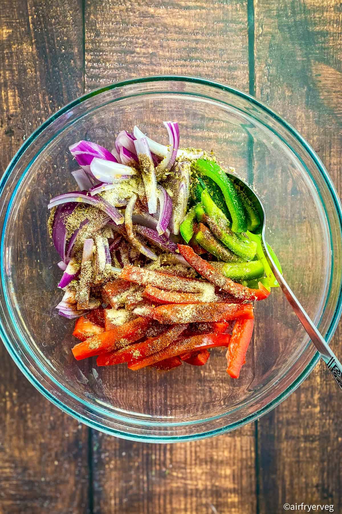 Bell peppers and onions in a bowl with seasonings.
